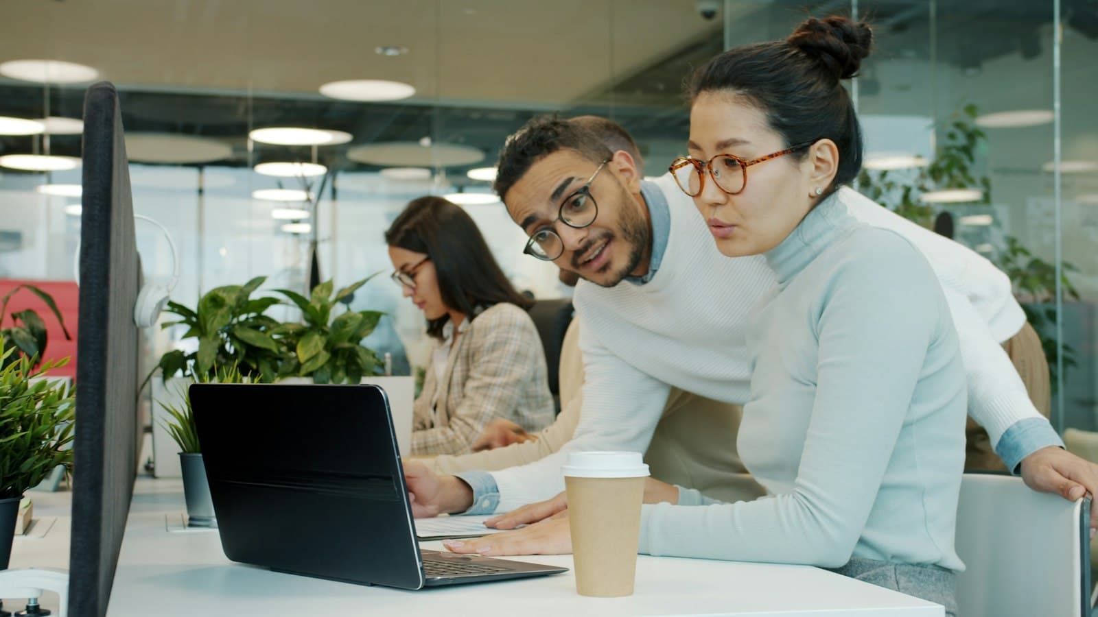 Two colleagues looking at a laptop screen together in an office