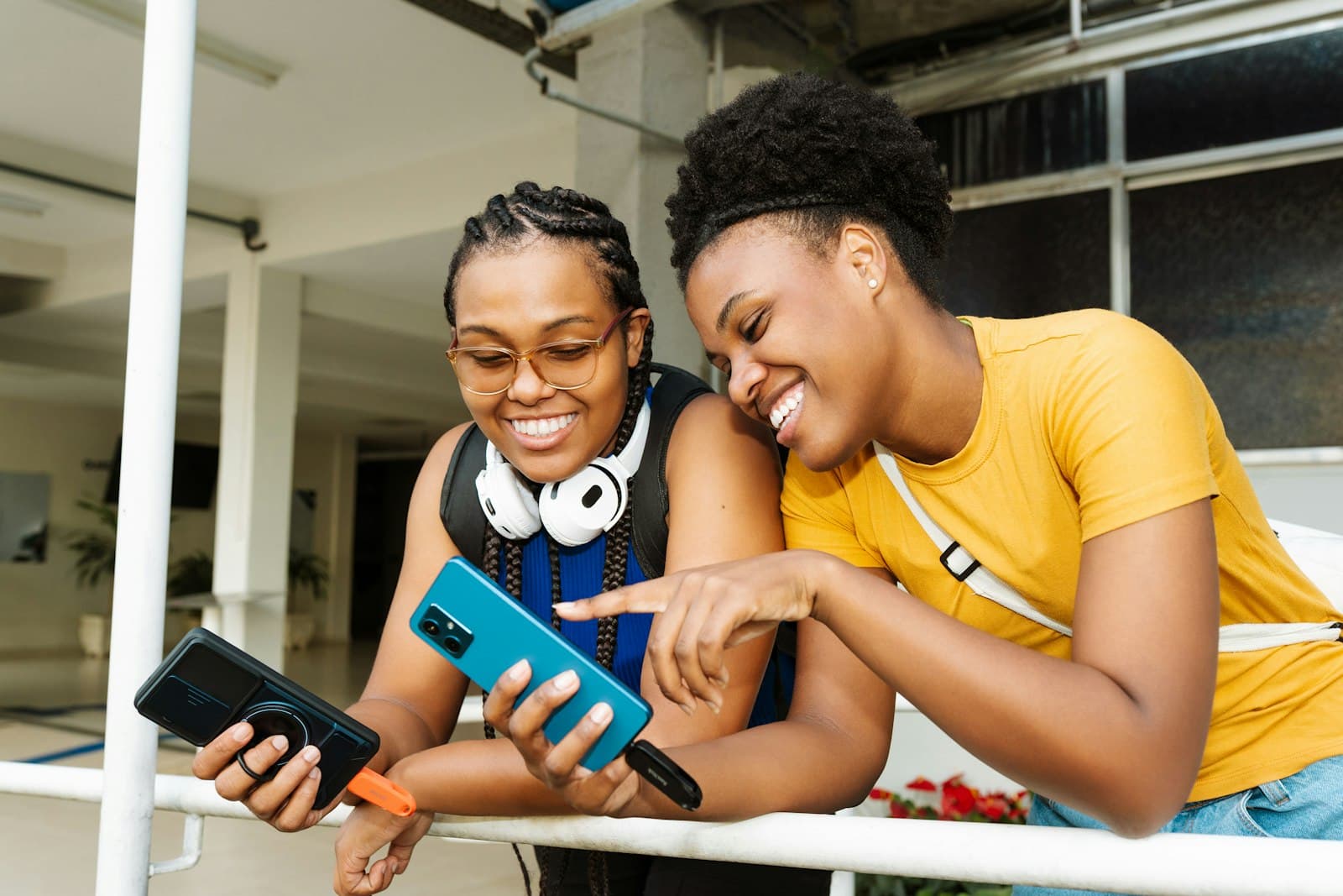 Two friends laughing as one shows the other something on her phone